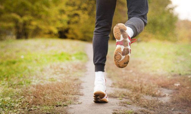 Man running along a park path, healthcare and problem concept - close-up of an unhappy person suffering from pain in the leg or knee outdoors - Foto, Imagem