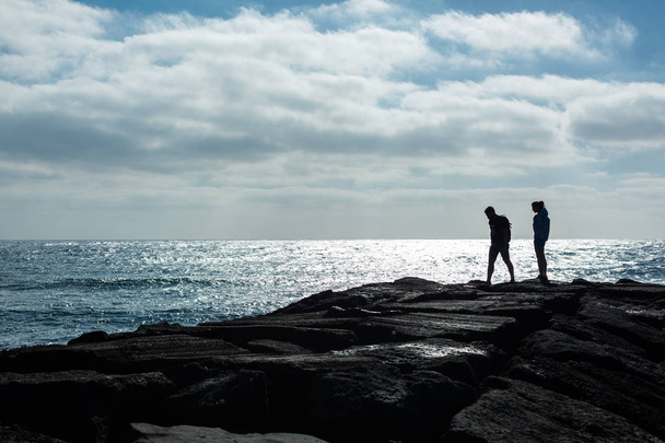 Silhouettes d'un homme et d'une femme sur une jetée de pierre contre l'océan. Île de Lanzarote, Espagne
. - Photo, image