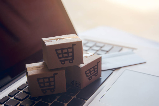 Shopping online concept - Shopping service on The online web. with payment by credit card and offers home delivery. parcel or Paper cartons with a shopping cart logo on a laptop keyboar - Photo, Image