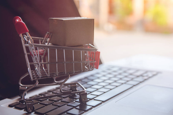 Shopping online concept - Shopping service on The online web. with payment by credit card and offers home delivery. parcel or Paper cartons with a shopping cart on a laptop keyboar - Photo, Image