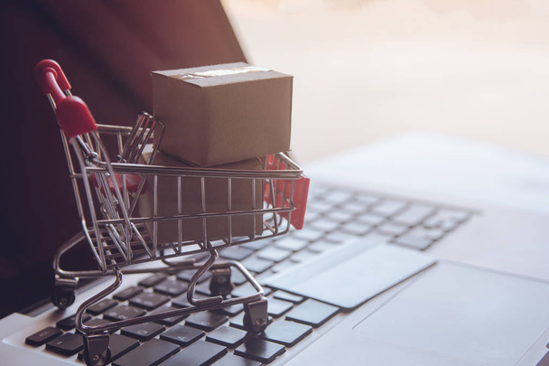 Shopping online concept - Shopping service on The online web. with payment by credit card and offers home delivery. parcel or Paper cartons with a shopping cart on a laptop keyboar - Photo, Image