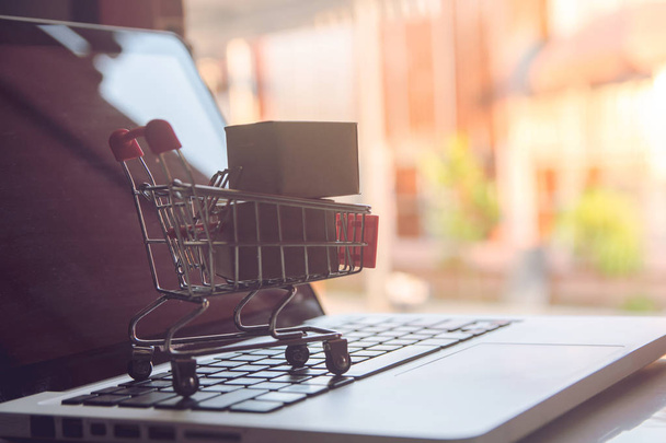 Shopping online concept - Shopping service on The online web. with payment by credit card and offers home delivery. parcel or Paper cartons with a shopping cart on a laptop keyboar - Foto, afbeelding
