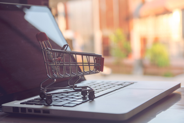 Shopping online concept - Shopping service on The online web. offers home delivery. Empty shopping cart on a laptop keyboard - Фото, изображение