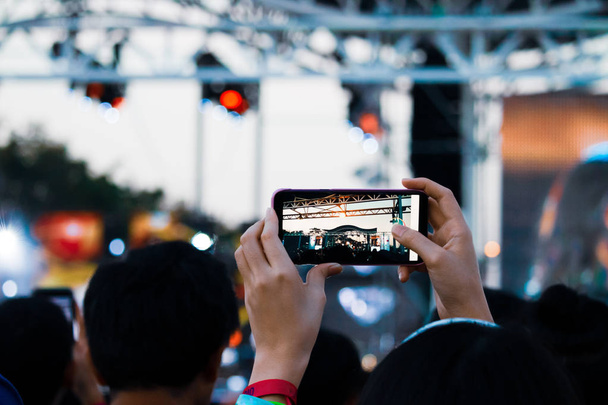 Hand mit Smartphone nimmt Live-Musik-Festival auf, Fotografieren von Konzertbühne, Live-Konzert, Musikfestival - Foto, Bild