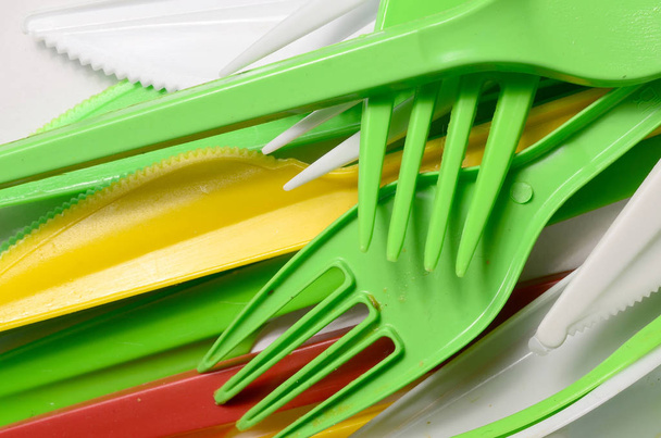 Pilha de amarelo brilhante, verde e branco usado utensílios de cozinha de plástico. Problema ecológico. Poluição plástica
 - Foto, Imagem