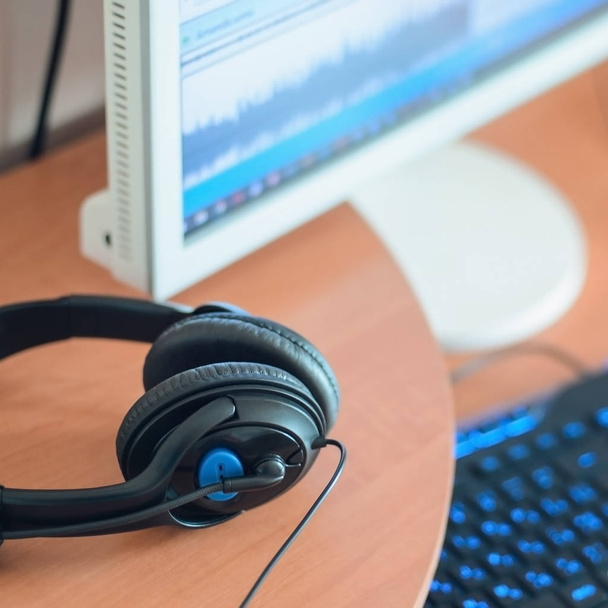 Big black headphones lie on the wooden desktop of the sound designer. Workplace for music creator. Selective focus - Photo, Image