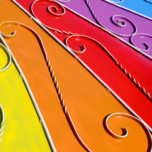 Metalen textuur van een stuk van gekleurde muur met een gesmede patroon. Regenboogkleuren - Foto, afbeelding