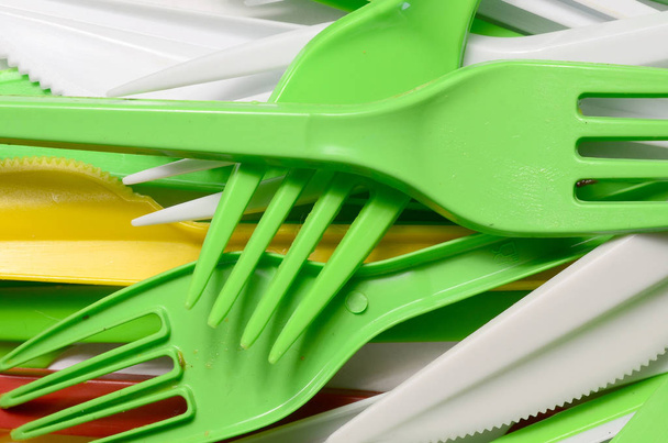 Pilha de amarelo brilhante, verde e branco usado utensílios de cozinha de plástico. Problema ecológico. Poluição plástica
 - Foto, Imagem
