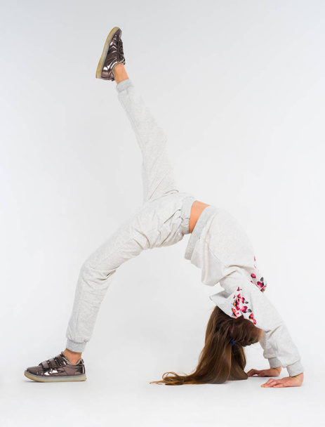 Little girl do gymnastic exercises on white background - Фото, зображення