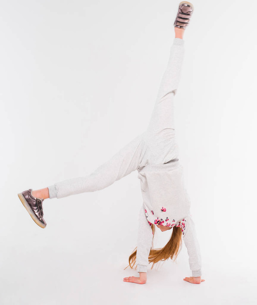 Aktivní holčička na bílém pozadí dělá handstand - Fotografie, Obrázek