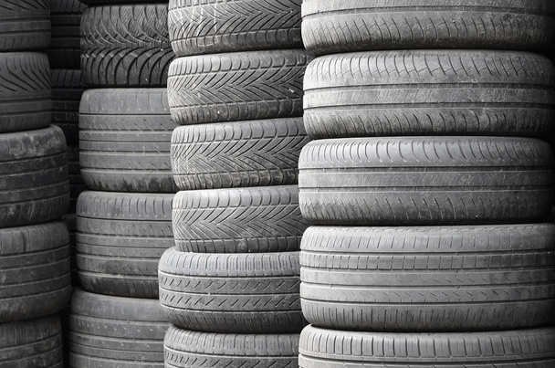 Neumáticos viejos usados apilados con altos pilotes en el garaje secundario de la tienda de piezas de automóviles de cerca
 - Foto, imagen