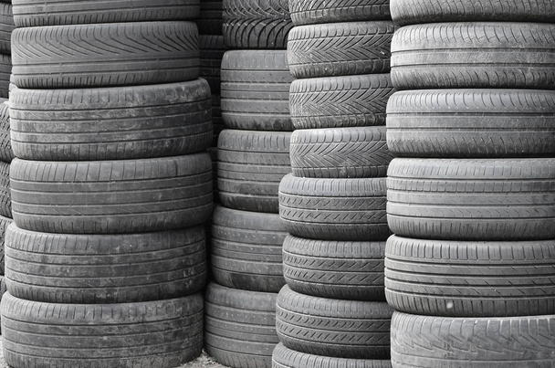 Старые подержанные шины, сложенные с высокими сваями в гараже вторичных автозапчастей.
 - Фото, изображение