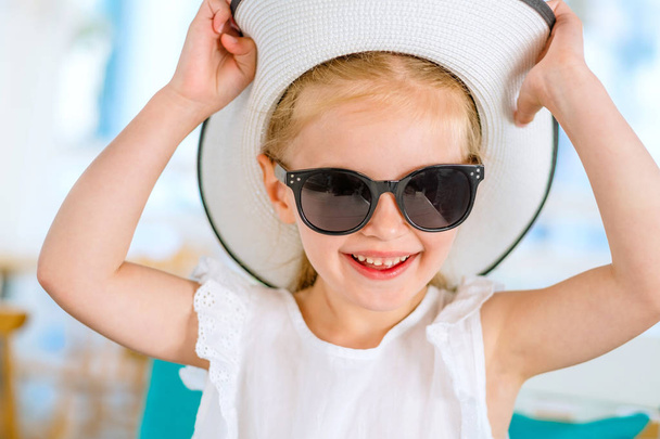 Little laughing blond girl in black sunglasses - Fotó, kép