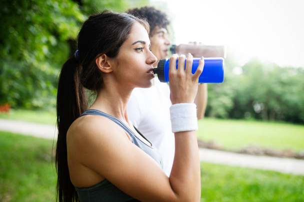 Pareja bebe agua después de correr para reponer energía e hidratar
 - Foto, Imagen