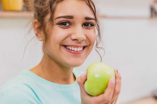 Happy Young Woman Eating Apple on Kitchen. Diet. Dieting concept. Healthy food. - Фото, зображення