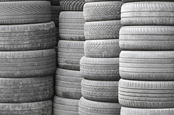 Neumáticos viejos usados apilados con altos pilotes en el garaje secundario de la tienda de piezas de automóviles de cerca
 - Foto, imagen