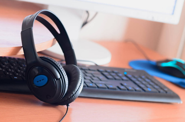 Big black headphones lie on the wooden desktop of the sound designer. Workplace for music creator. Selective focus - 写真・画像