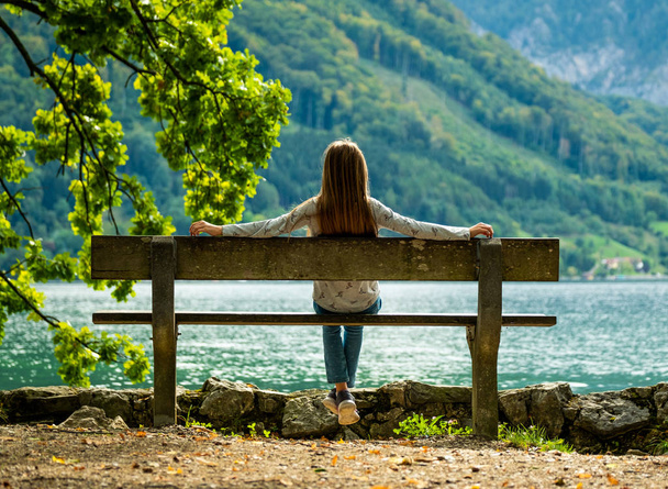 Маленькая девочка сидит на скамейке и смотрит на речные пейзажи
 - Фото, изображение