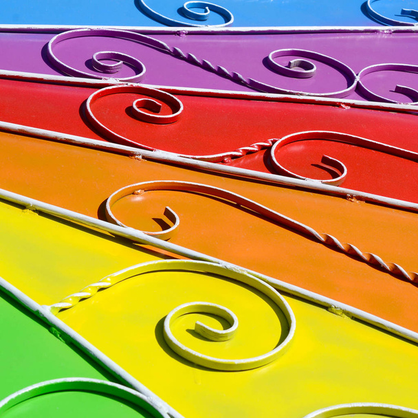 Metal texture of a piece of colored wall with a forged pattern. Rainbow colors - Photo, Image