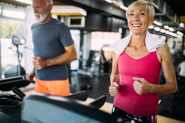 Mature people running on a treadmill in health club. - Фото, зображення