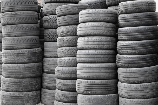 Старые подержанные шины, сложенные с высокими сваями в гараже вторичных автозапчастей.
 - Фото, изображение