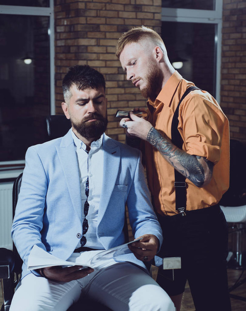 Balm on dry body parts to moisturize skin. Beard styling cut. Ideas about Barbershop and Barber salon. Man visiting hairstylist in barber shop. Trims. Barber shaving a bearded man in a barber shop. - Foto, Imagem