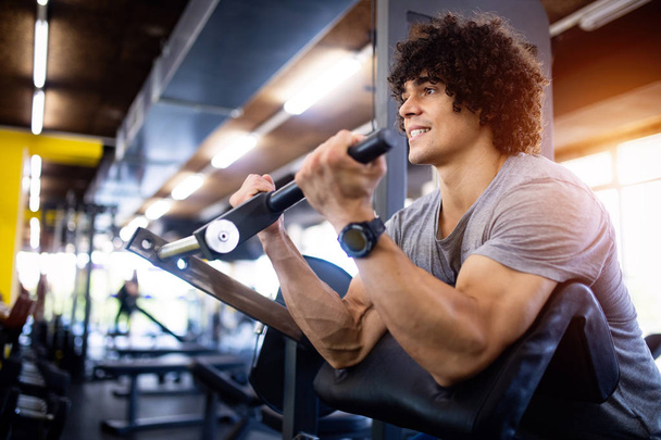 Young handsome man doing exercises in gym - 写真・画像