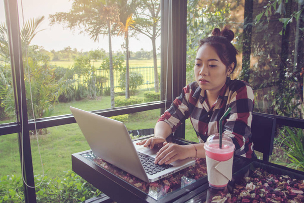 Giovane asiatica seduta da sola alla caffetteria a lavorare su un computer portatile
 - Foto, immagini