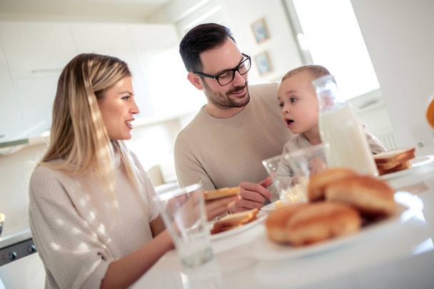 家族、食事、人コンセプト - 幸せな母、父と息子の朝食を家庭で有する. - 写真・画像