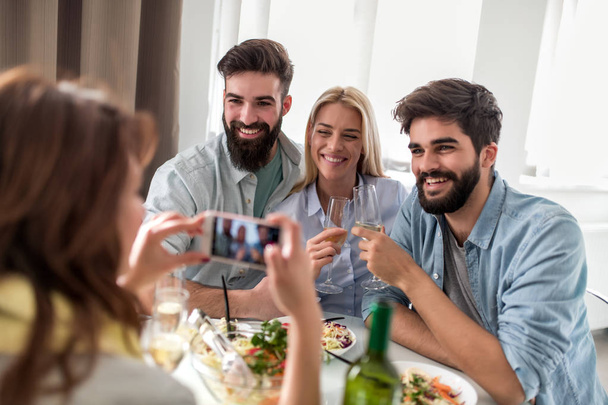Gruppe fröhlicher Menschen amüsiert sich zusammen, trinkt Wein und fotografiert. - Foto, Bild