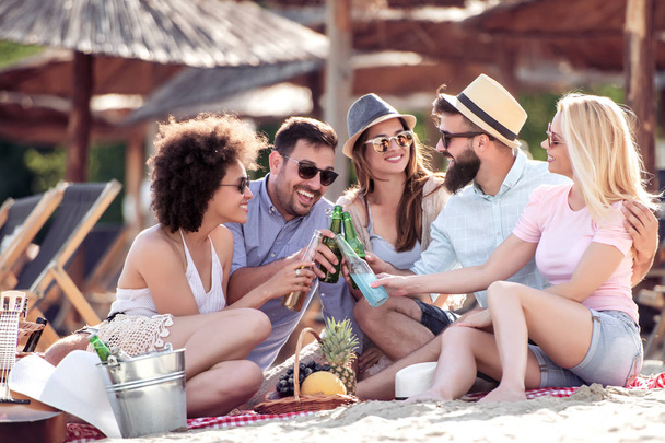 Grupa osób korzystających w dobry nastrój i piknik na plaży. Koncepcja styl życia, Podróże, szczęście i wakacje. - Zdjęcie, obraz