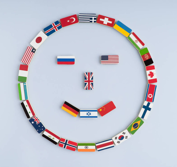 ilustração de uma face sorridente de bandeiras nacionais em dominós. Conceito de paz e da Comunidade das Nações e da ordem mundial
 - Foto, Imagem