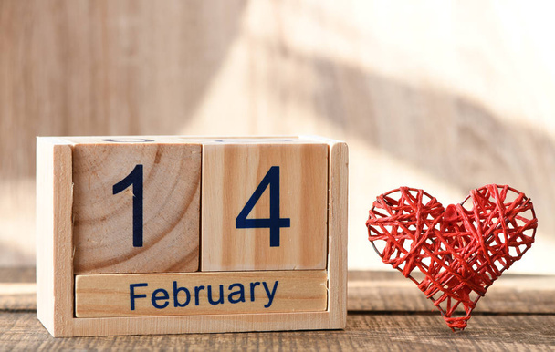 Форма серця ручної роботи та дерев'яний календар з датою 14 лютого на столі
 - Фото, зображення