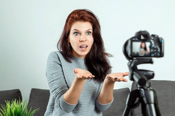 A young beautiful girl is sitting in front of a DSLR and recording a Vlog, close-up. Blogger, blogging, technology, online money, online courses. copy space. - Foto, Imagen