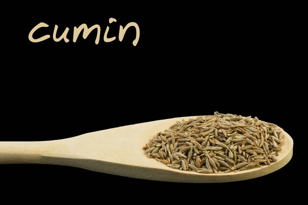 cumin on wooden spoon isolated on black background - Photo, Image