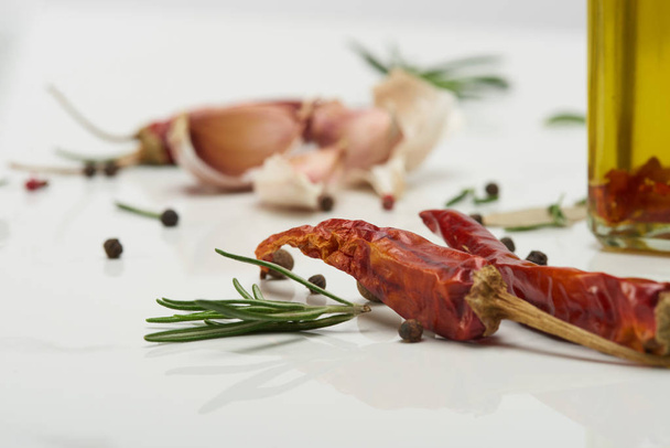 peperoncino rosso piccante, foglie di rosmarino, spicchi d'aglio e pepe nero su superficie bianca
 - Foto, immagini