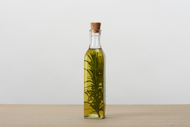 garrafa de óleo com sabor de cortiça com ramo de alecrim dentro na superfície cinza
 - Foto, Imagem