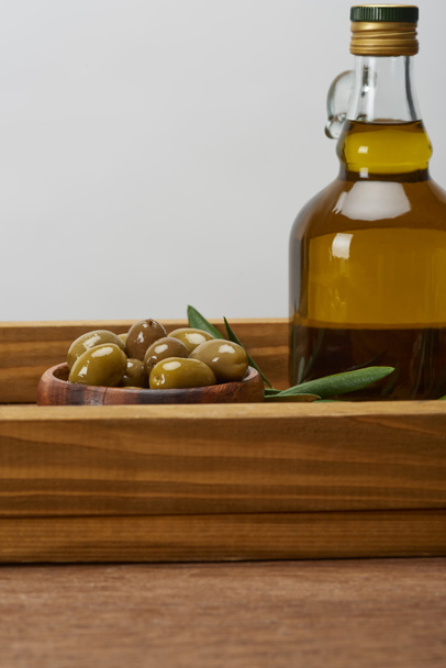 wooden tray with bowl of olives, olive tree leaves and bottle of oil on brown surface  - Φωτογραφία, εικόνα