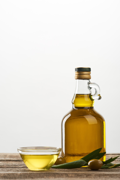 bowl and bottle of oil, olive tree leaves and olives isolated on grey  - Fotografie, Obrázek