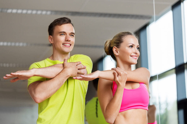 smiling man and woman exercising in gym - Foto, imagen