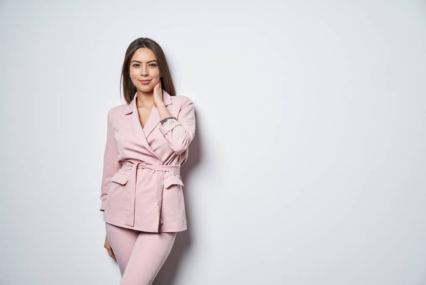 Woman wearing pink suit standing by white wall - Photo, Image