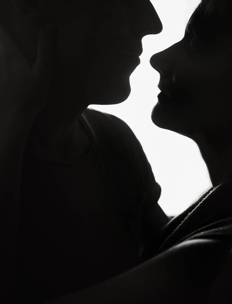 couple in love silhouette looking in the eyes behind them white light - Foto, imagen