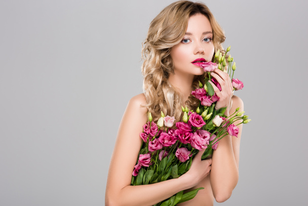 nude beautiful woman posing with spring Eustoma flowers bouquet isolated on grey - 写真・画像