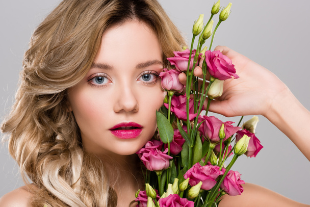 beautiful woman posing with spring Eustoma flowers bouquet isolated on grey - 写真・画像