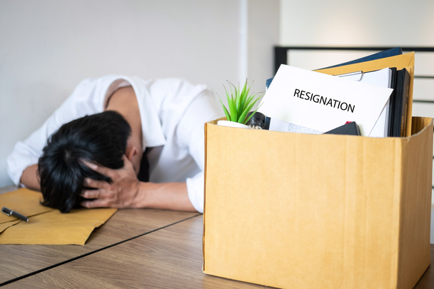 Stressed businessman will being resignation and packing belongings company and files into brown cardboard box, changing and resigning from work concept. - Photo, Image