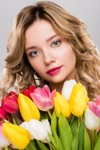 young attractive spring woman holding bouquet of colorful tulips isolated on grey  - Фото, изображение