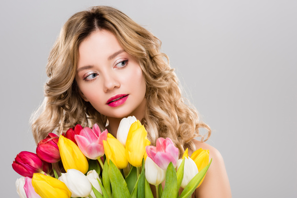 nuori houkutteleva kevät nainen tilalla kimppu värikkäitä tulppaaneja ja etsii pois eristetty harmaa
  - Valokuva, kuva