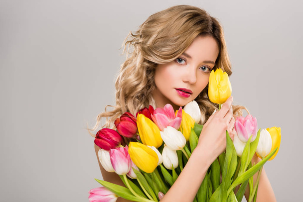 young nude attractive spring woman holding bouquet of colorful tulips isolated on grey  - Фото, изображение