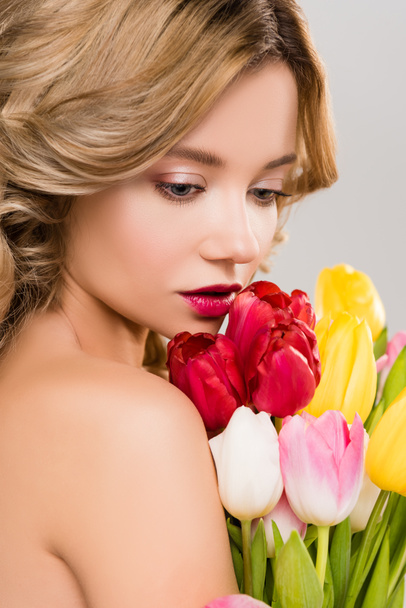 tender nude spring woman holding bouquet of colorful tulips isolated on grey  - Foto, imagen