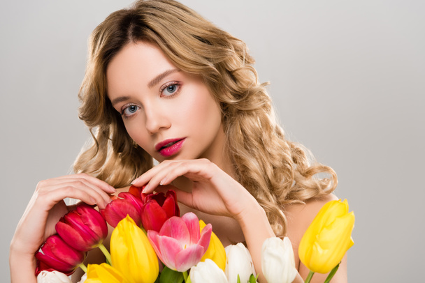 молодая обнаженная нежная привлекательная весенняя женщина дотрагивается до букета красочных тюльпанов, изолированных на сером
  - Фото, изображение